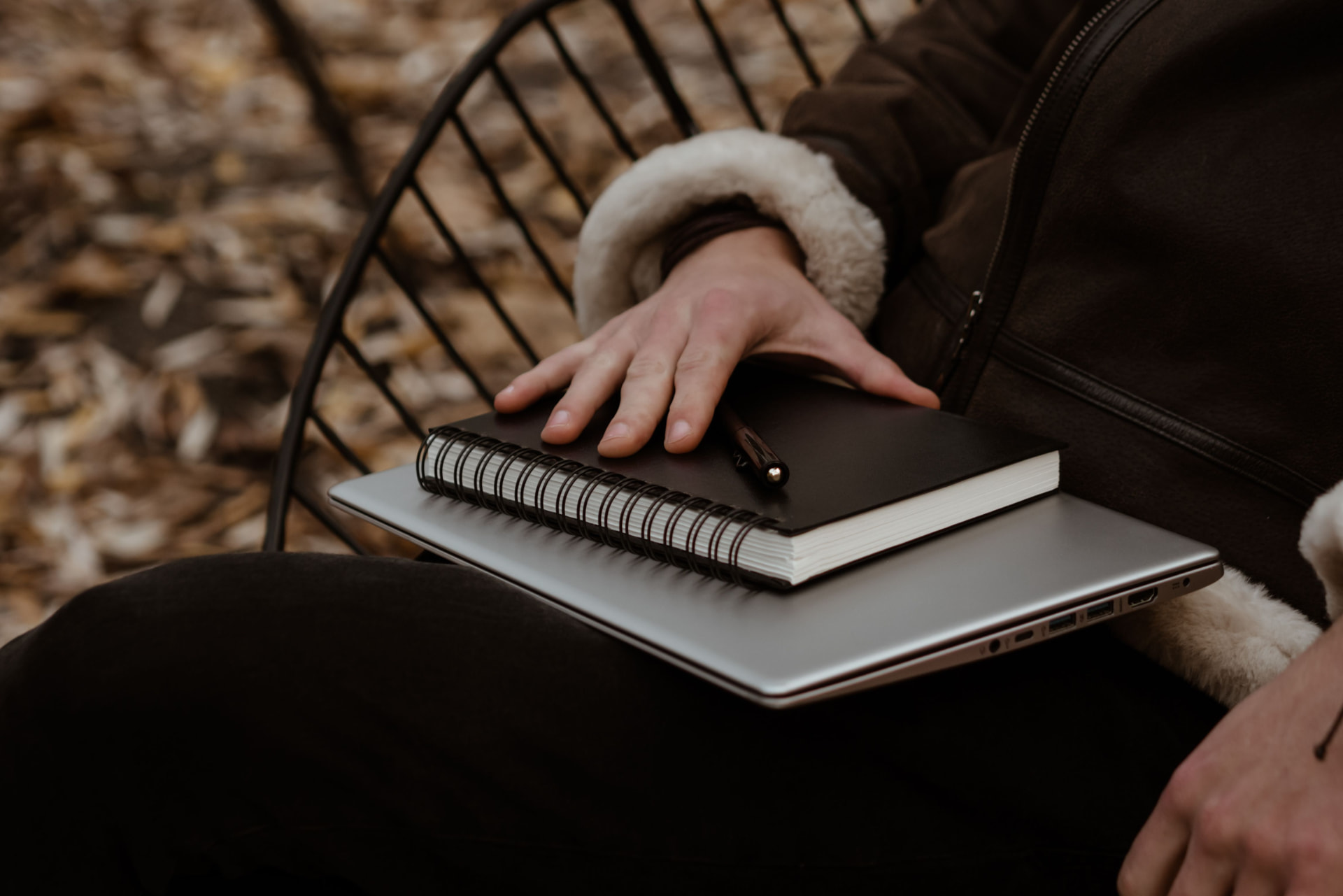Hand resting on a journal and laptop outdoors