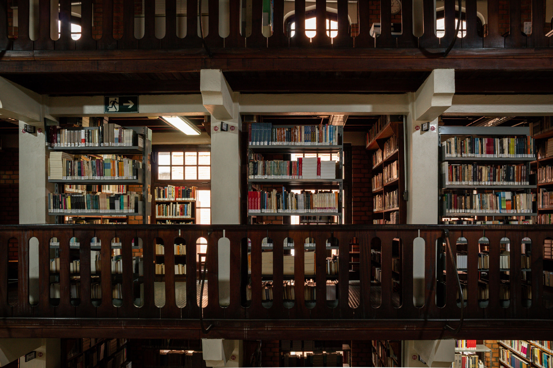Wooden library balcony overlooking rows of bookshelves